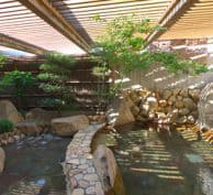 『高知黒潮ホテル』の露天風呂。淡い色の石と植え込みの緑が特徴的です。