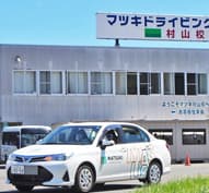 校舎の前を走る教習車（普通車）。
